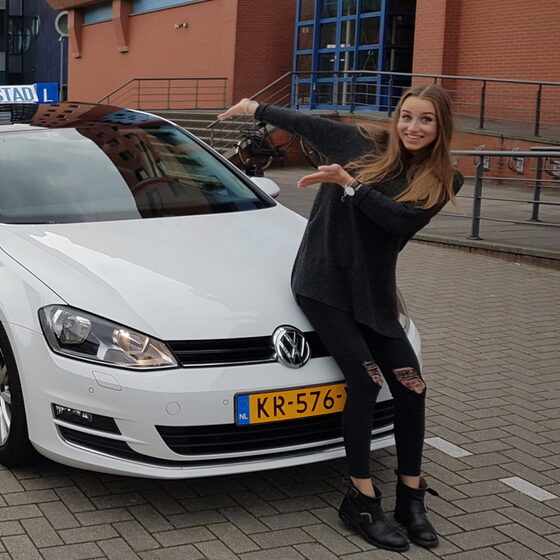 Geslaagde leerling bij de lesauto van Hofstad