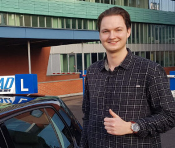 Geslaagde leerling bij de zwarte lesauto