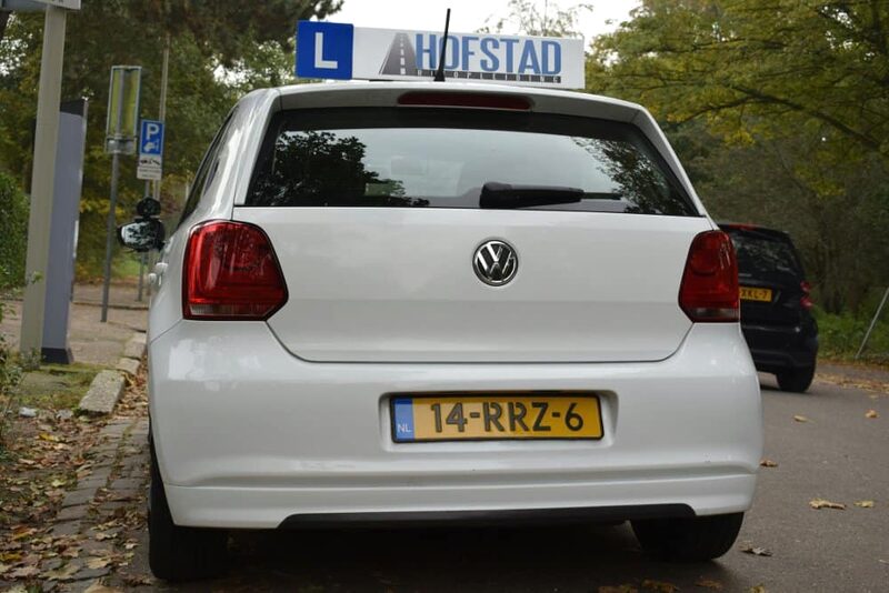 De witte lesauto van Hofstad Rijopleiding met daklichtbak